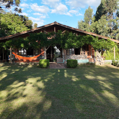 Fachada rústica com rede e gramado amplo — descanso e conexão com a natureza
